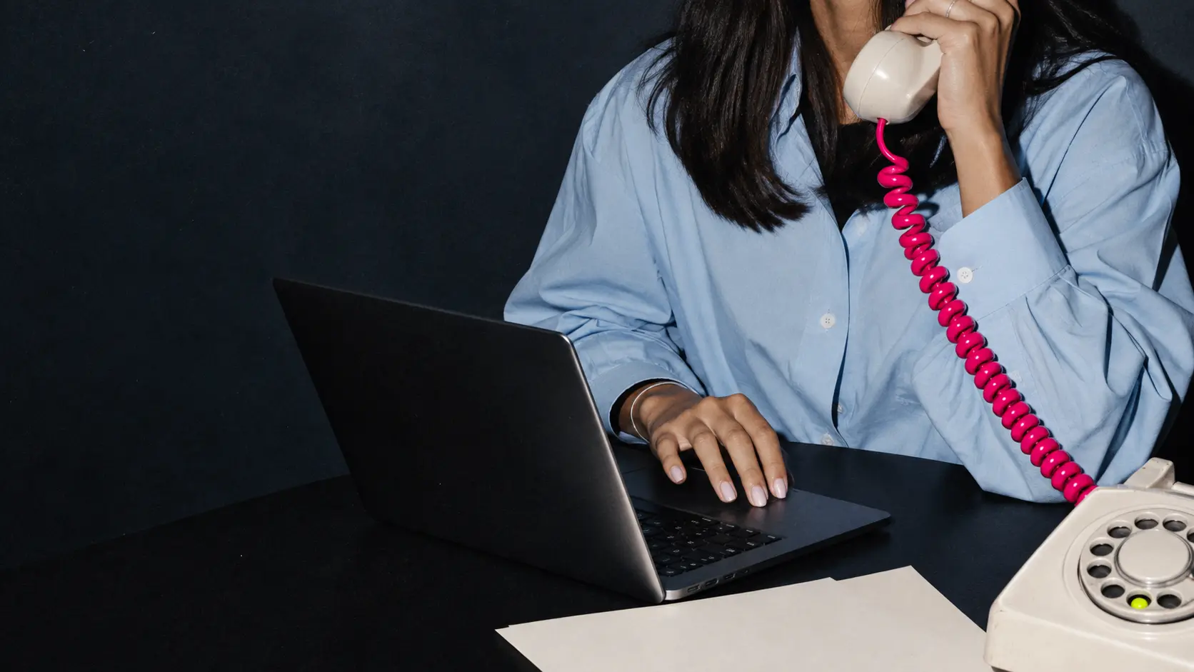 Marketing, comunicação e criatividade — Comuniqa Profissional ao computador com um telefone analógico, numa composição editorial da Comuniqa